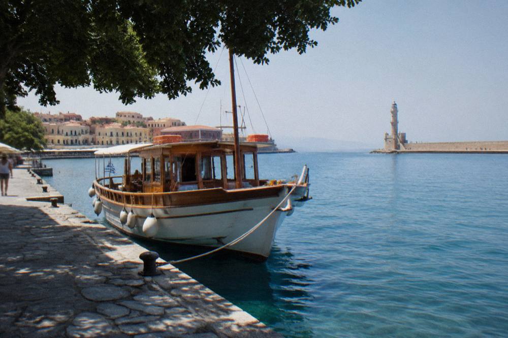 A wooden excursion boat tied up at a small Cretan quay in clear morning light
