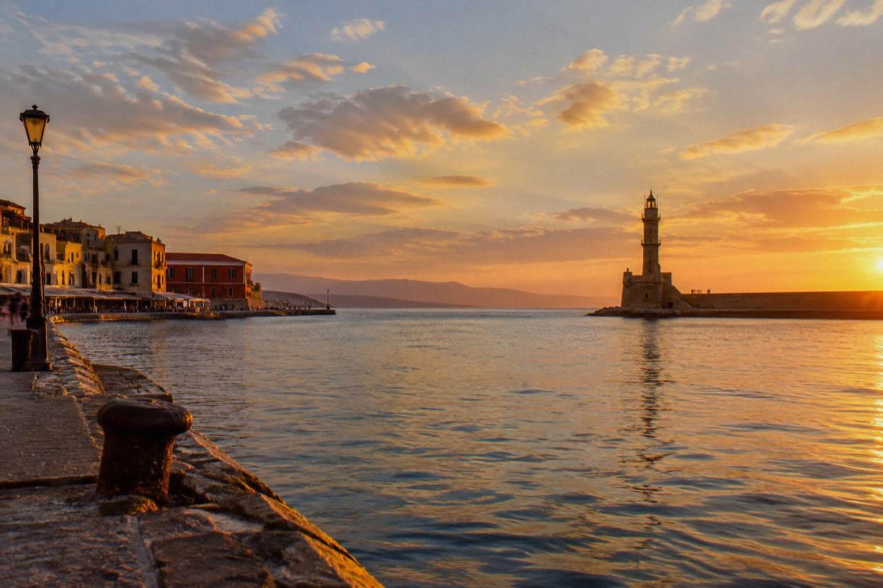 The Venetian Harbour of Chania at golden hour with the lighthouse at the end of the breakwater