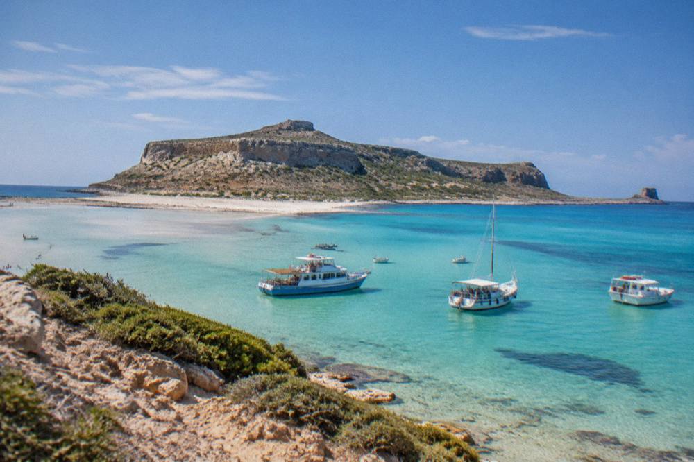 Boats moored in the shallow turquoise water of Balos Lagoon below the Gramvousa peninsula