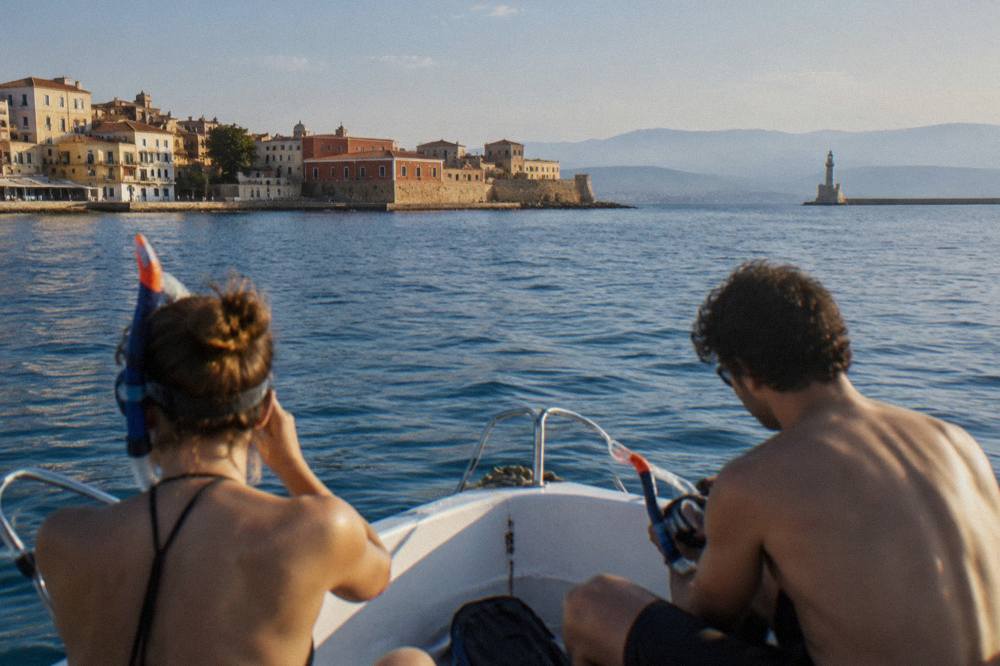 Two people sharing a small boat trip with snorkeling gear near the Chania coastline