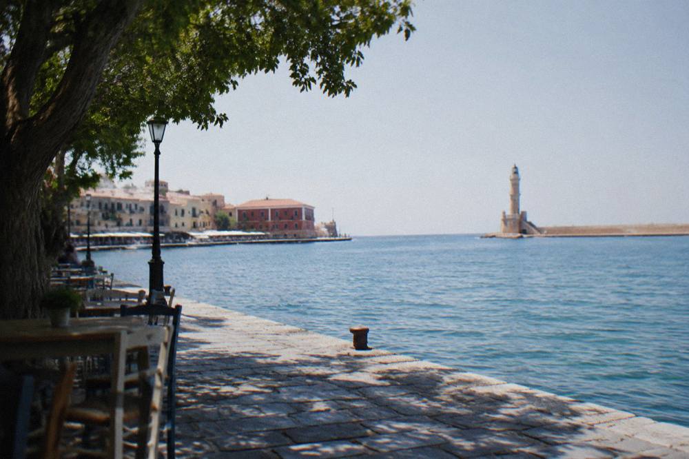 Harbour front of Chania at the water's edge with the lighthouse in the distance