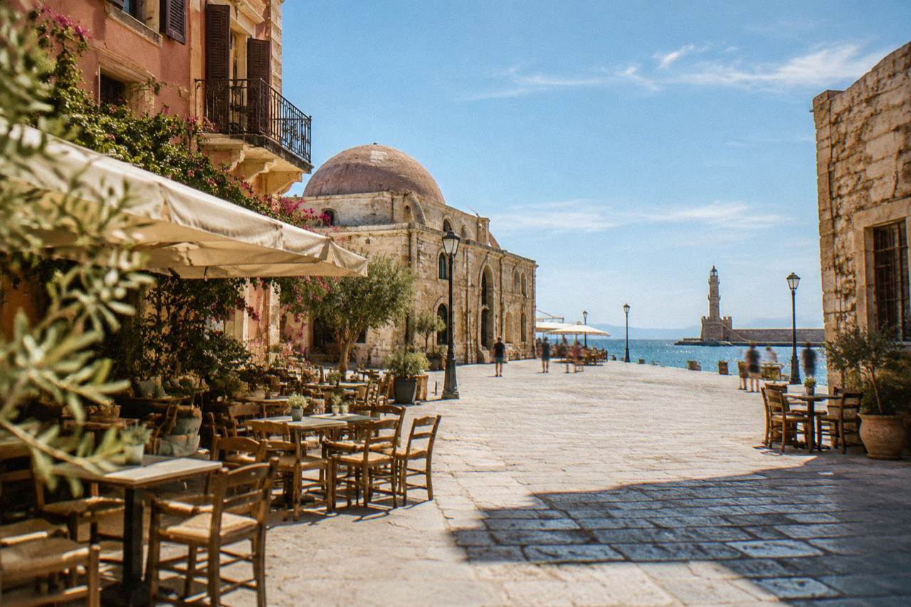 A sunlit square in Chania Old Town with stone buildings and cafe tables