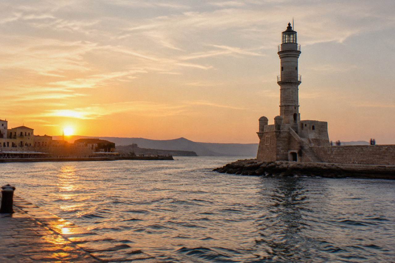 The Venetian Harbour of Chania at golden hour with the lighthouse at the end of the breakwater