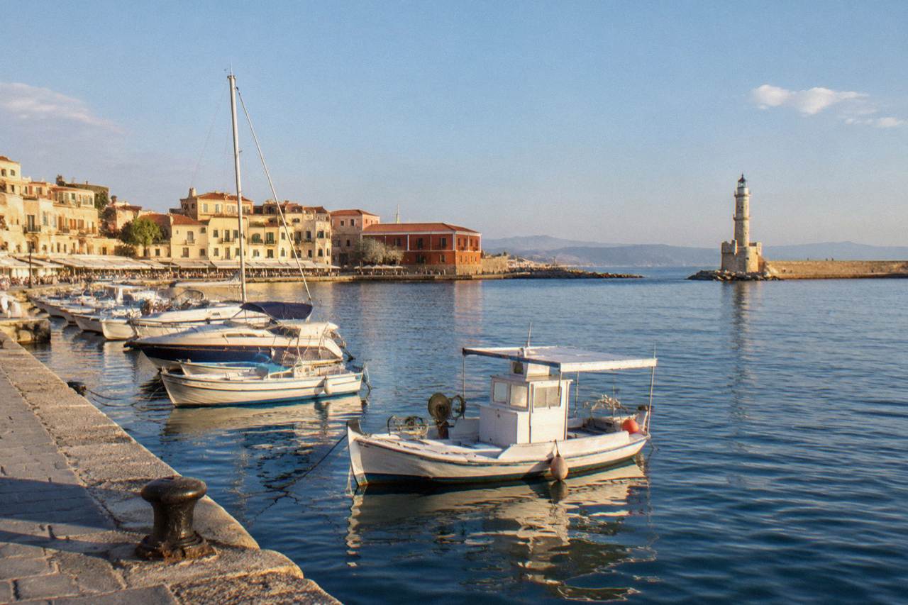 The Venetian Harbour of Chania with the lighthouse at the end of the breakwater and boats moored along the quay