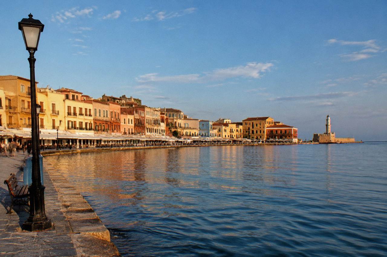 Pastel coloured buildings along the Venetian Harbour waterfront in Chania at golden hour