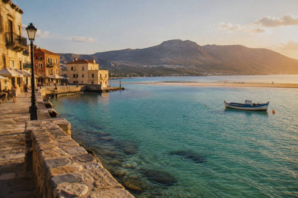 Turquoise shallow water of a Cretan lagoon with a sandy spit and hills in the background