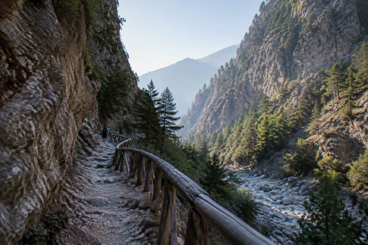A rocky gorge path winding between steep stone walls under a clear sky