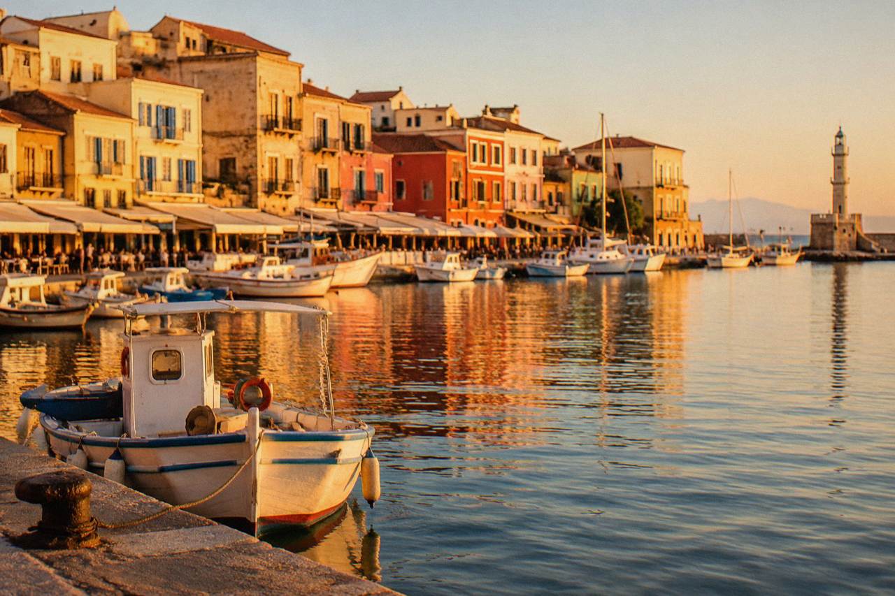 Colourful facades along the Venetian Harbour waterfront in Chania with boats moored in the calm water