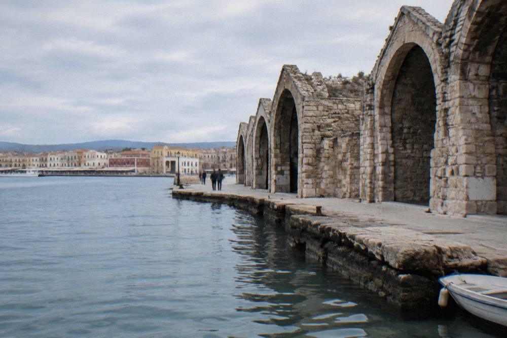 The stone arches of the Venetian shipyards, the Neoria, standing along the harbour edge in Chania