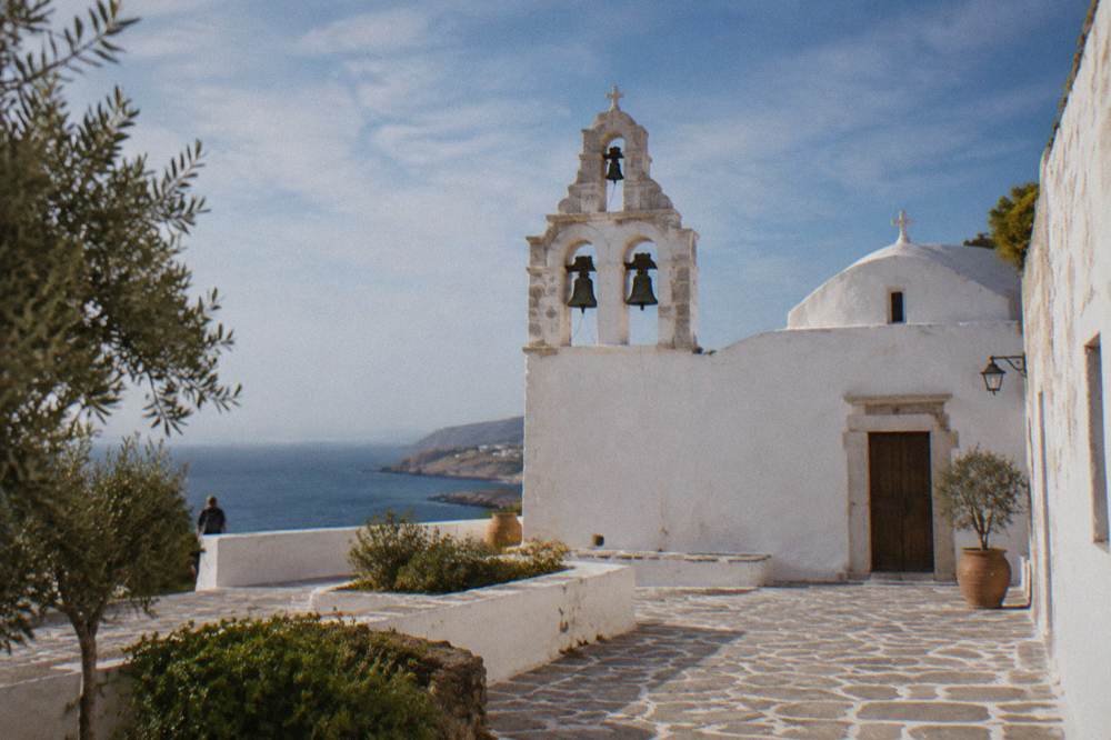 A whitewashed monastery courtyard with a bell tower under a blue sky