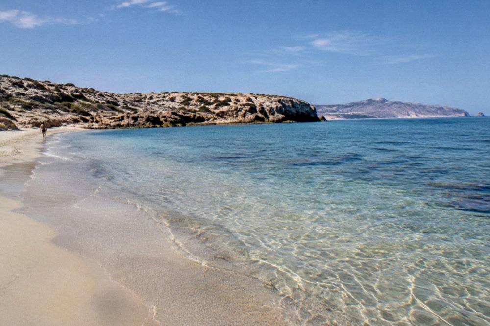 A quiet beach of pale sand with shallow clear water in early morning light