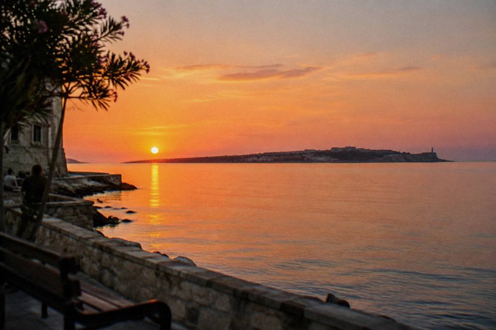A view across the water from Halepa toward a distant peninsula at sunset