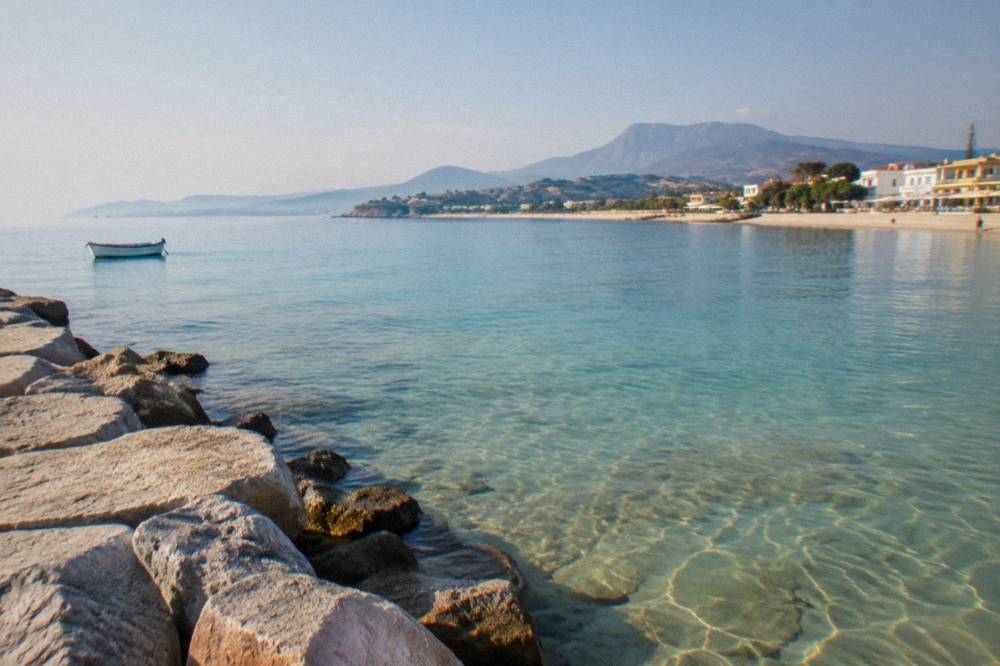 Clear shallow water over sand seen from a stone jetty at the edge of a bay