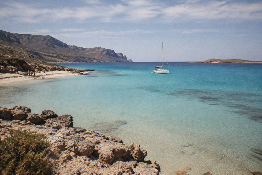 A turquoise lagoon shelving into shallow white sand with a boat anchored offshore