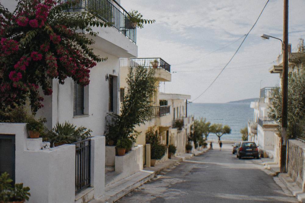 A quiet residential street of low white buildings with balconies a short walk from the sea