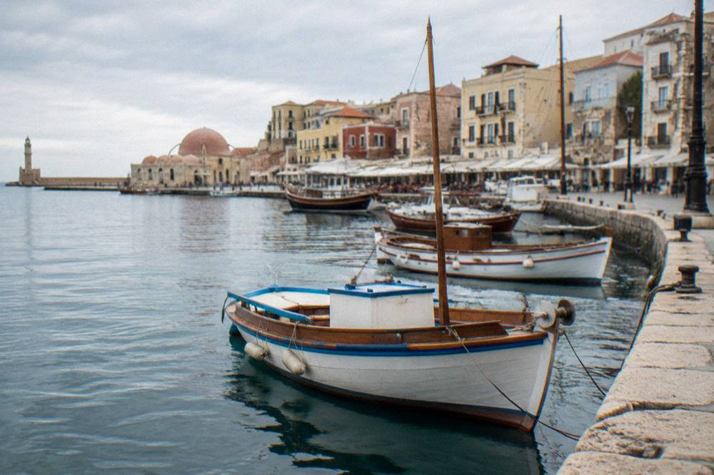 Wooden boats moored along the old harbour quay with stone buildings behind