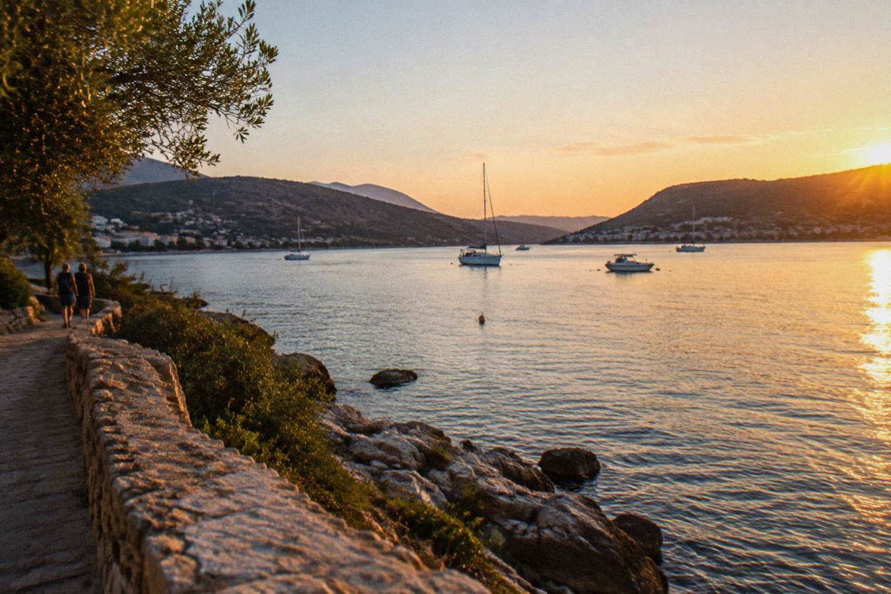 A wide natural bay with calm water, low hills on both shores and a few boats anchored offshore