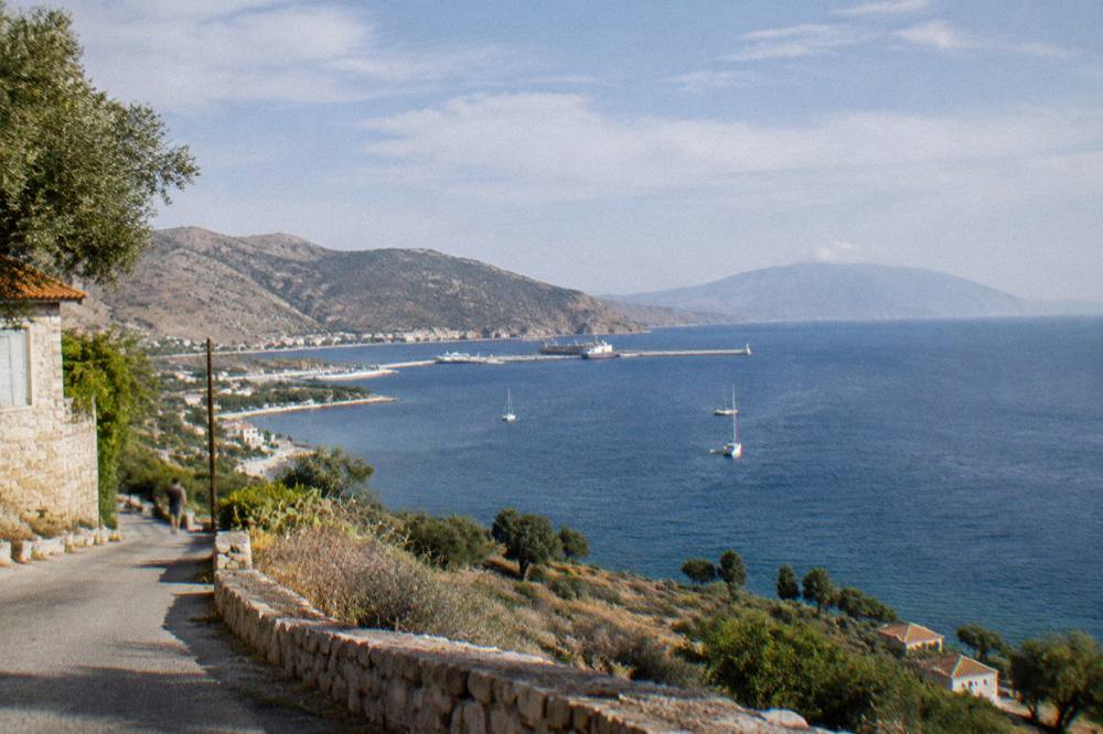 A sunny bay with deep blue water, dry hillsides and a hazy horizon toward a distant peninsula