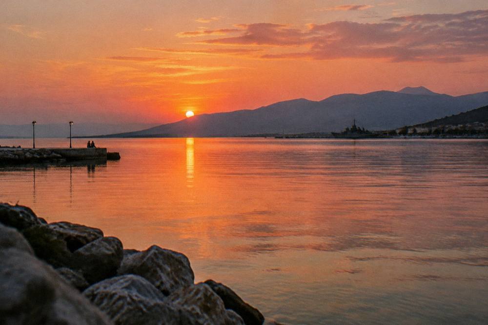 An evening view across a wide bay toward distant mountains, with the last light on the water