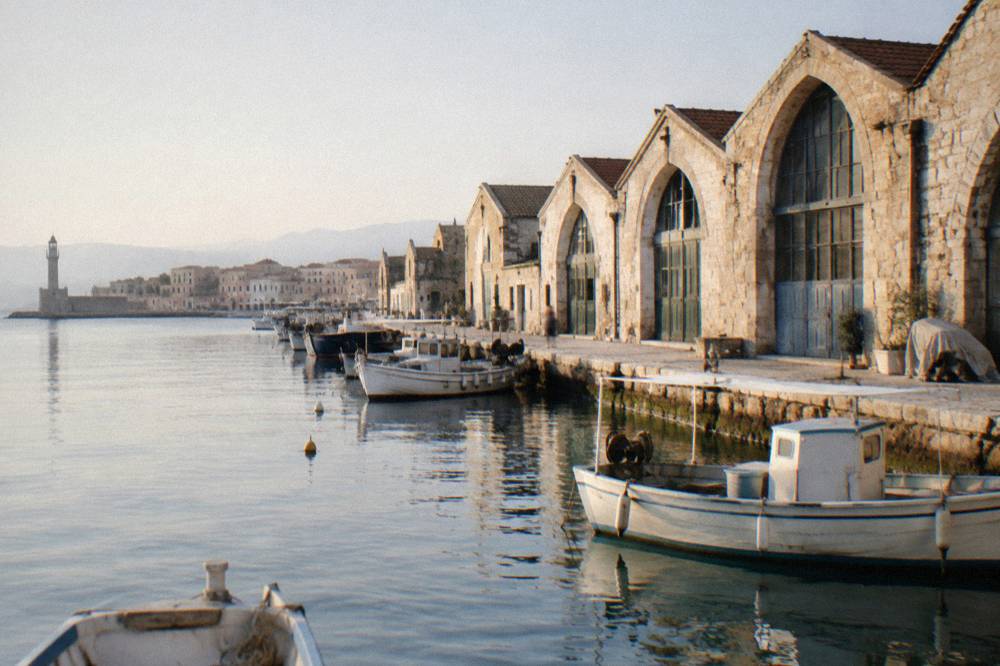 Row of stone shipyard buildings with arched fronts along the Chania harbour