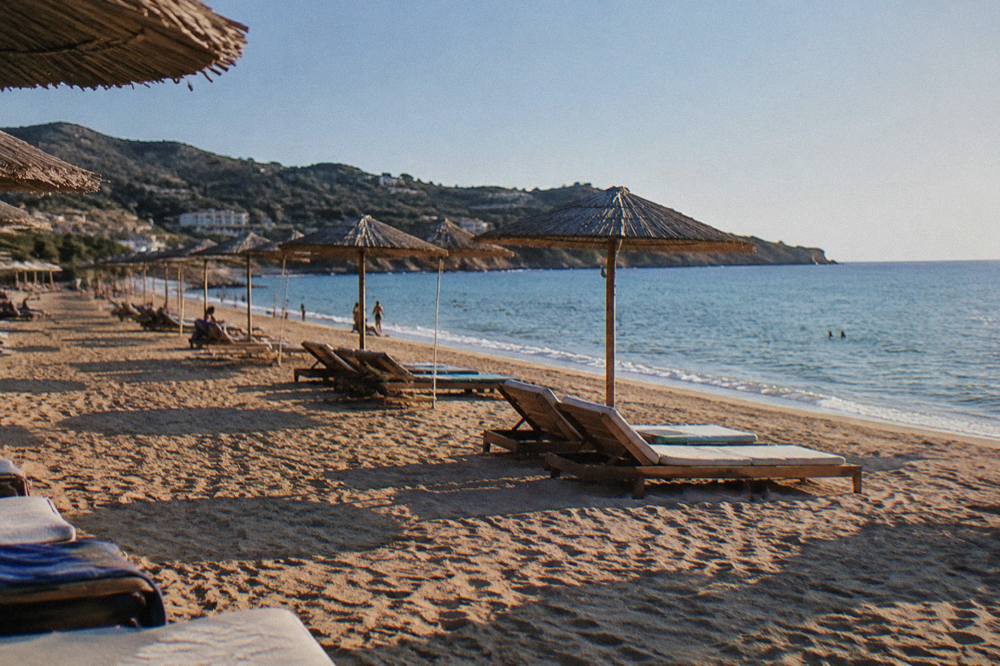 Sunbeds and umbrellas in rows on golden sand near the waterline
