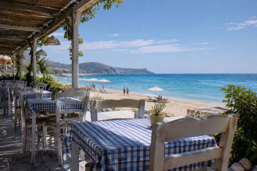A taverna terrace with tables and chairs facing the sea