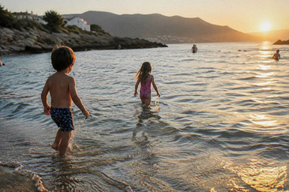 Children playing in shallow calm water at the edge of the sea
