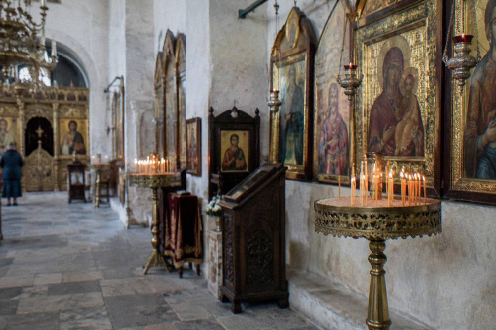A church interior with candle stands and gilded icons along the walls