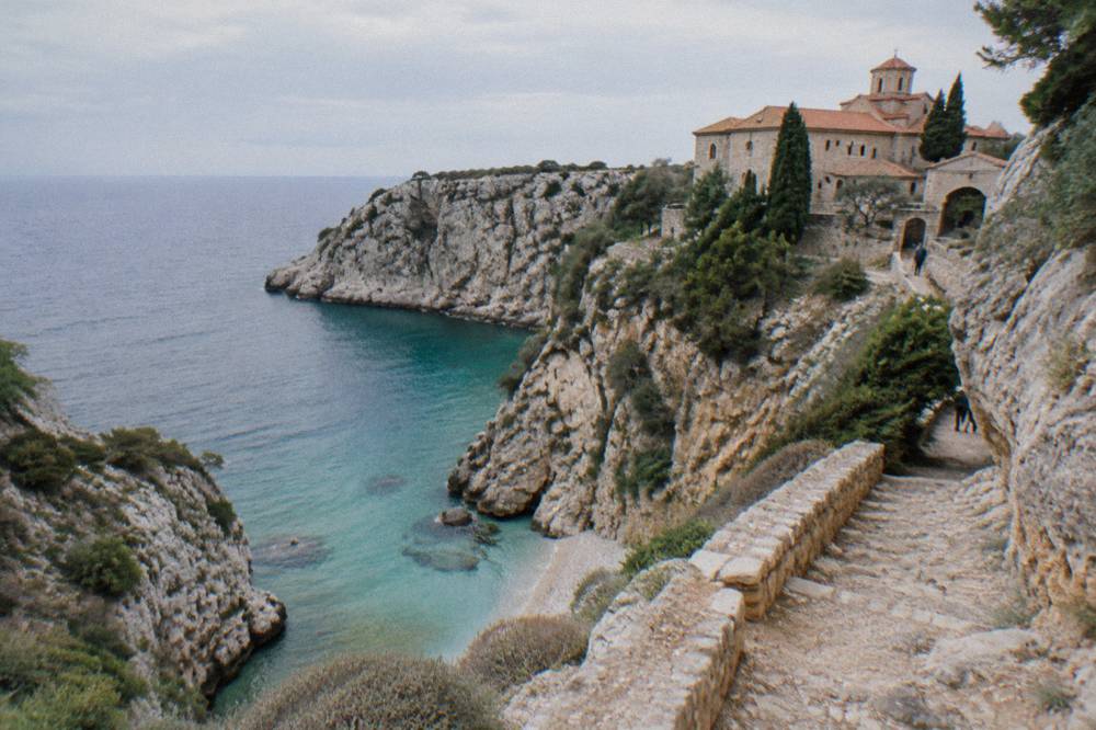 A steep limestone cove with turquoise water below a rocky path
