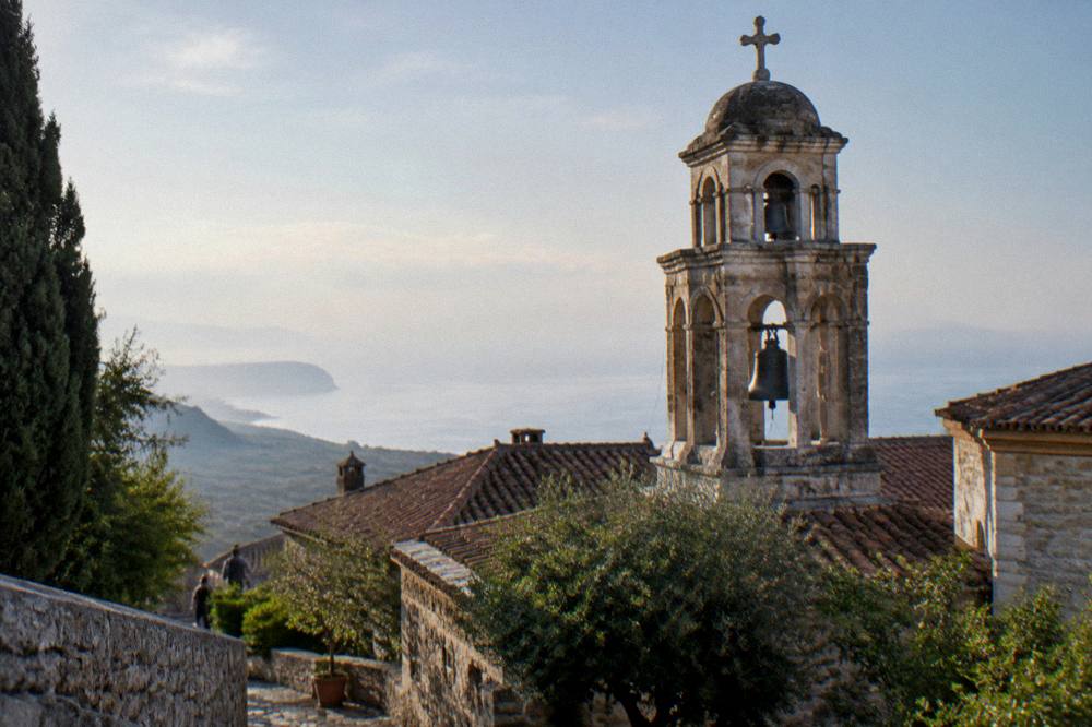 A bell tower above monastery rooftops with sea haze on the horizon