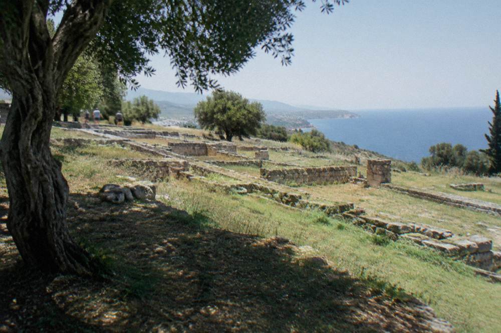 Rows of ancient stone foundation walls on a grassy slope under a clear sky