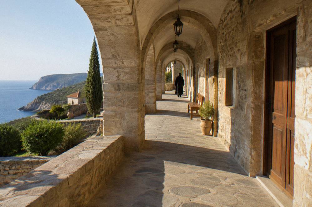 An arched stone walkway along a monastery building with wooden doors