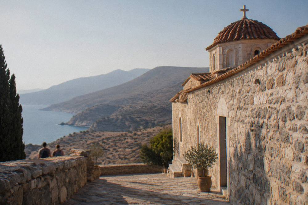 Sunlight falling on a stone monastery wall with dry rocky hills behind