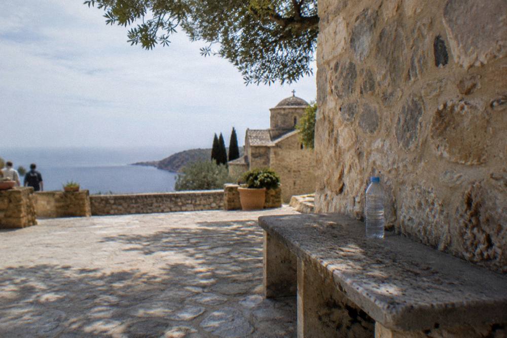 A shaded stone bench beside a monastery wall with a water bottle resting on it