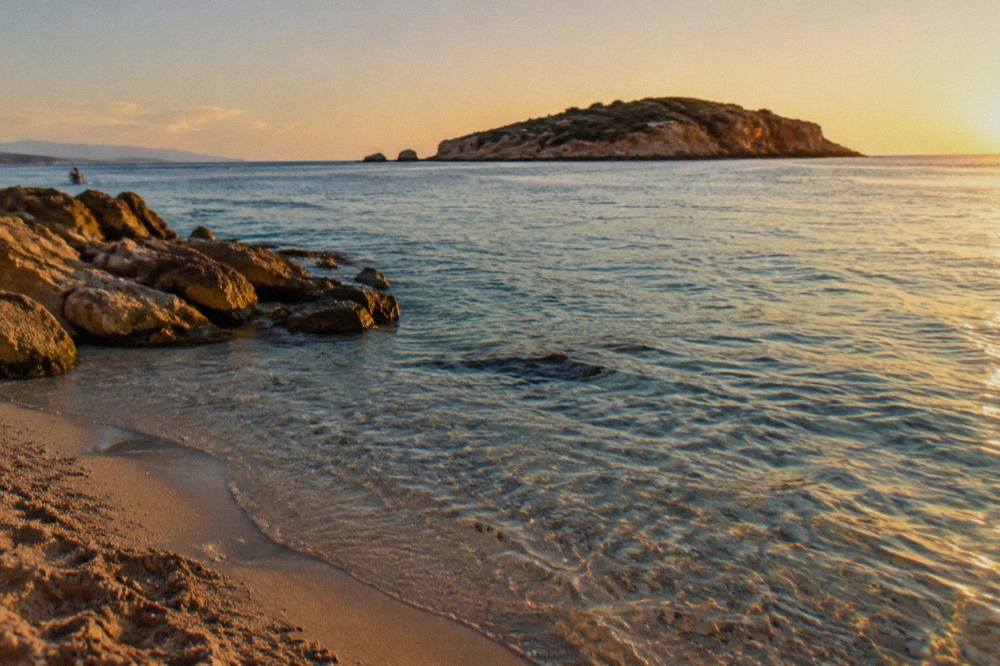 The small offshore island at Kalathas Beach seen across clear shallow water from the sand