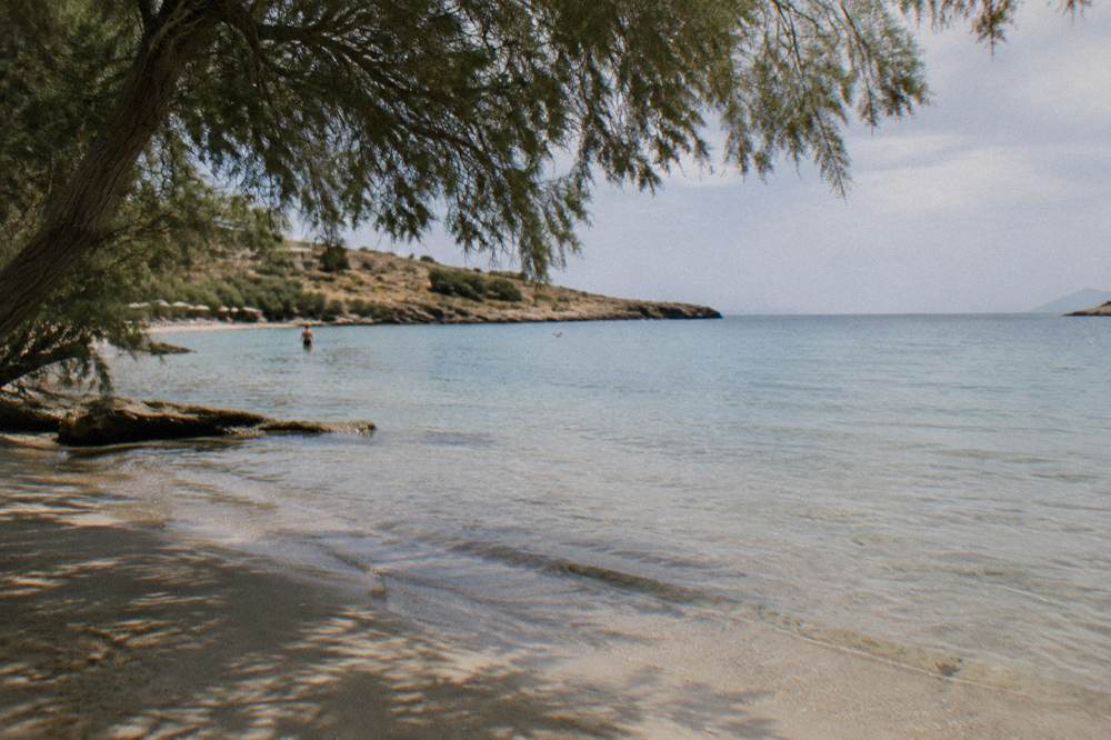 Shallow calm water over sand at Kalathas Beach with gentle shade under tamarisk trees