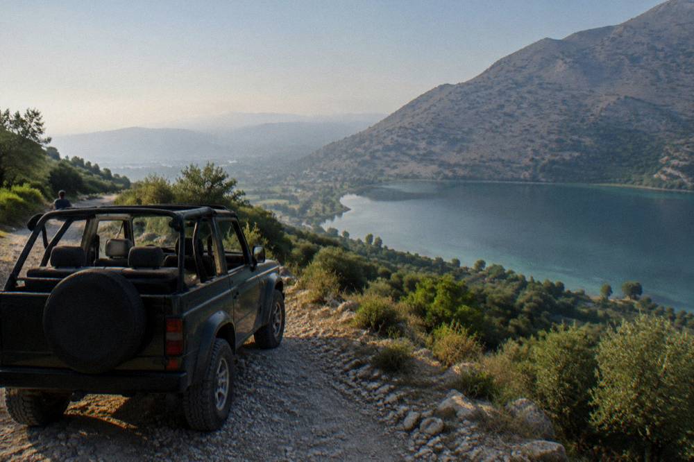 An open-top four by four vehicle parked on a mountain track above deep green valleys
