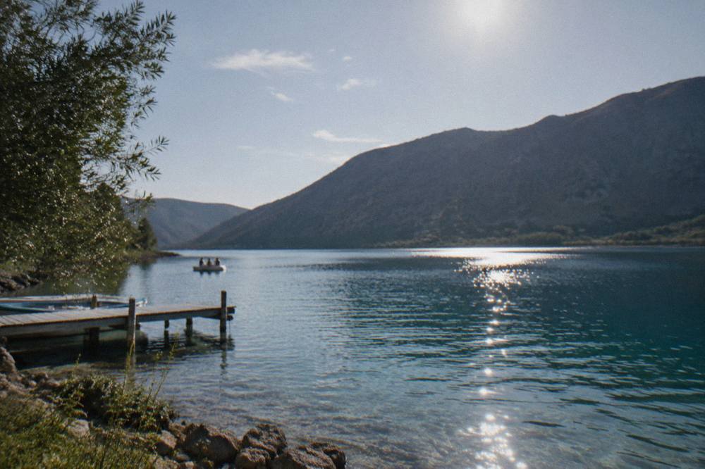 Sunlight over still lake water in late afternoon with dark hills silhouetted behind