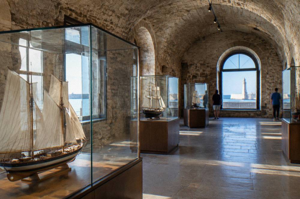 A stone vaulted room inside an old fortress with display cases of ship models