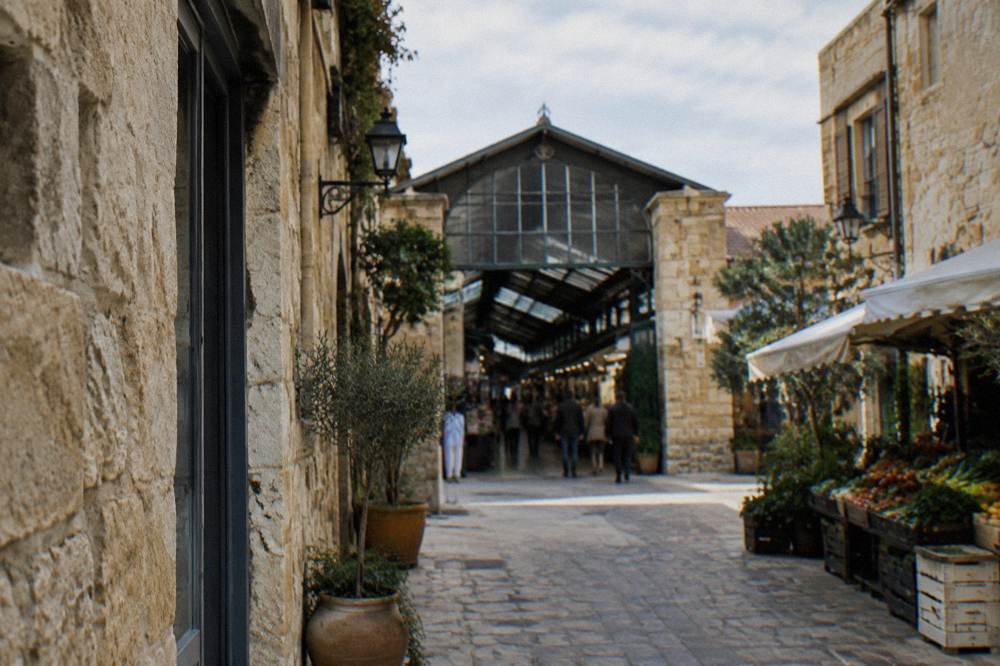 Narrow Old Town lane with stone facades leading toward the covered market entrance