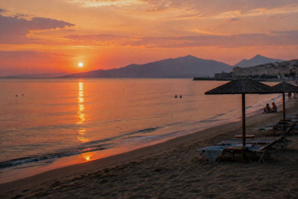 Evening light over a calm bay with the silhouette of mountains across the water