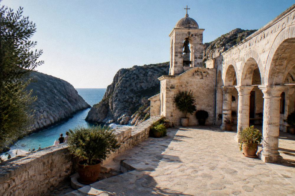 A pale stone monastery courtyard with arcades under a clear sky