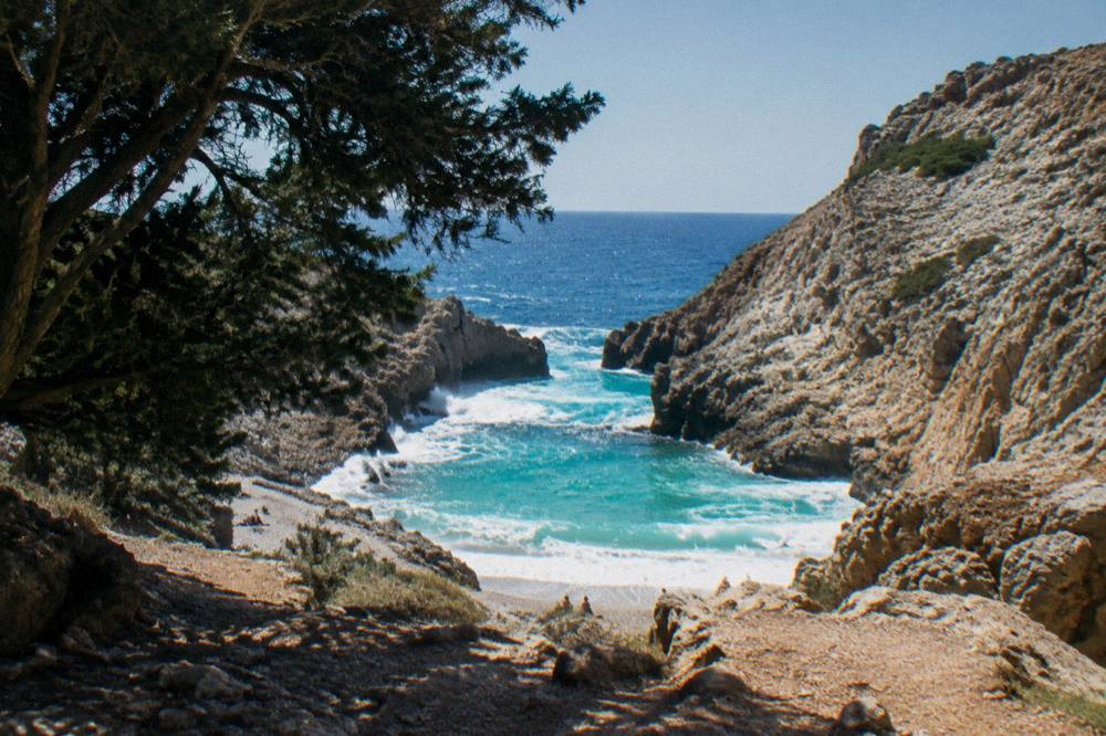 Waves breaking white against rocks at the mouth of a small cliff inlet