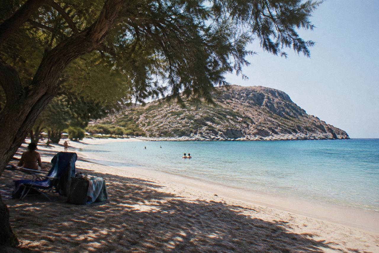 A calm sandy bay on the Akrotiri peninsula with a rocky headland rising over clear shallow water