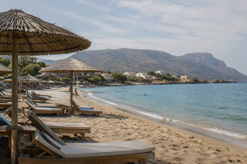 Sun loungers and umbrellas along the sand at a small Cretan beach village in the morning