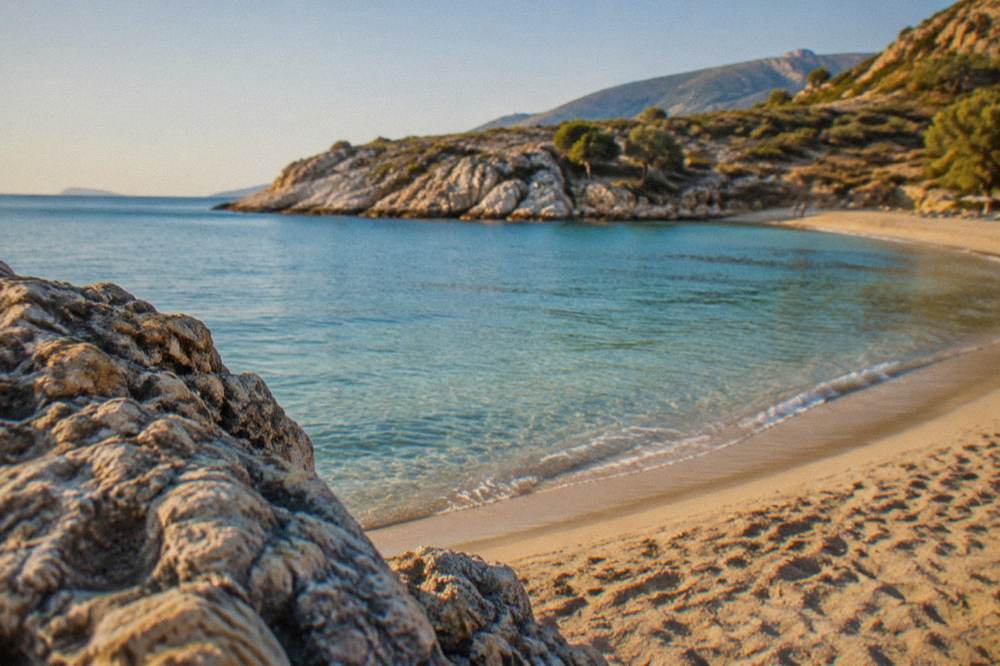 Empty sand and calm turquoise water at a small bay in late morning light