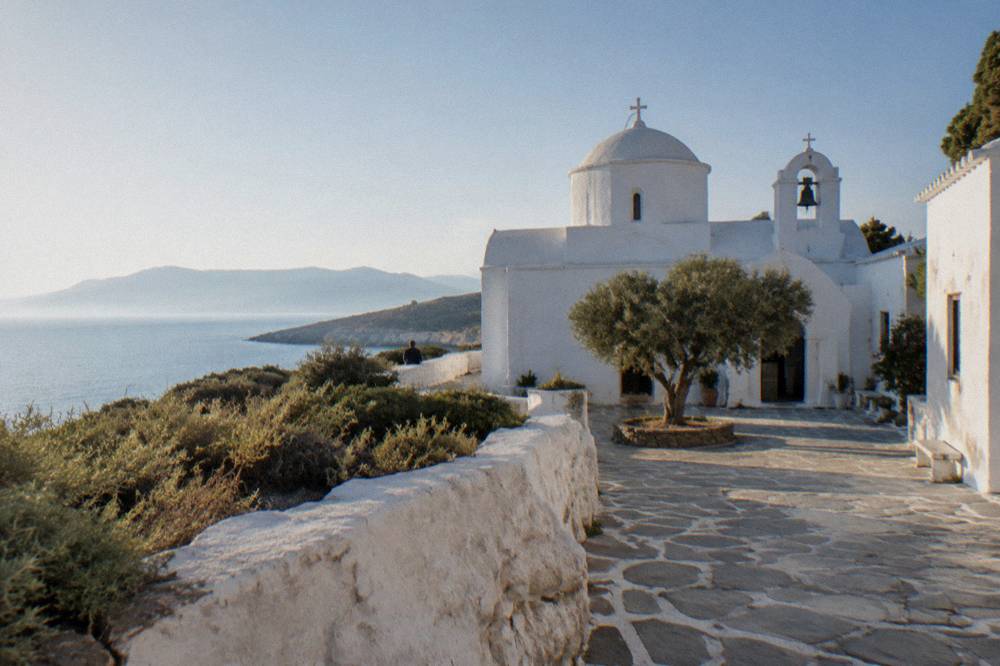 A white monastery building with a courtyard on the Akrotiri peninsula under a clear sky