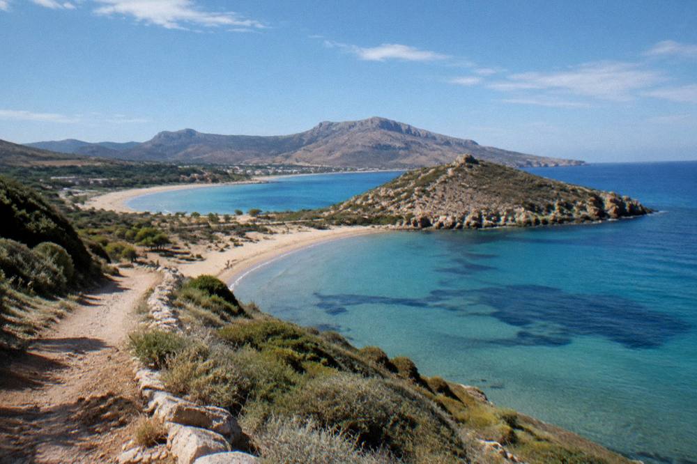 Two sandy bays on a Cretan peninsula seen from a headland path in afternoon light