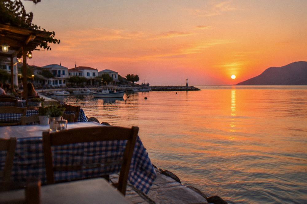 Evening light on a small Cretan harbour town with taverna tables near the water