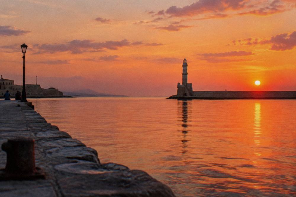 The lighthouse of Chania at sunset seen from the western mole of the Venetian Harbour